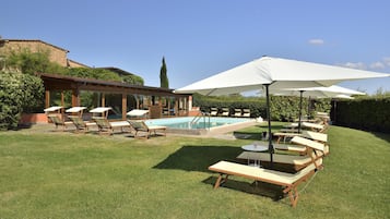 Una piscina al aire libre de temporada, sombrillas