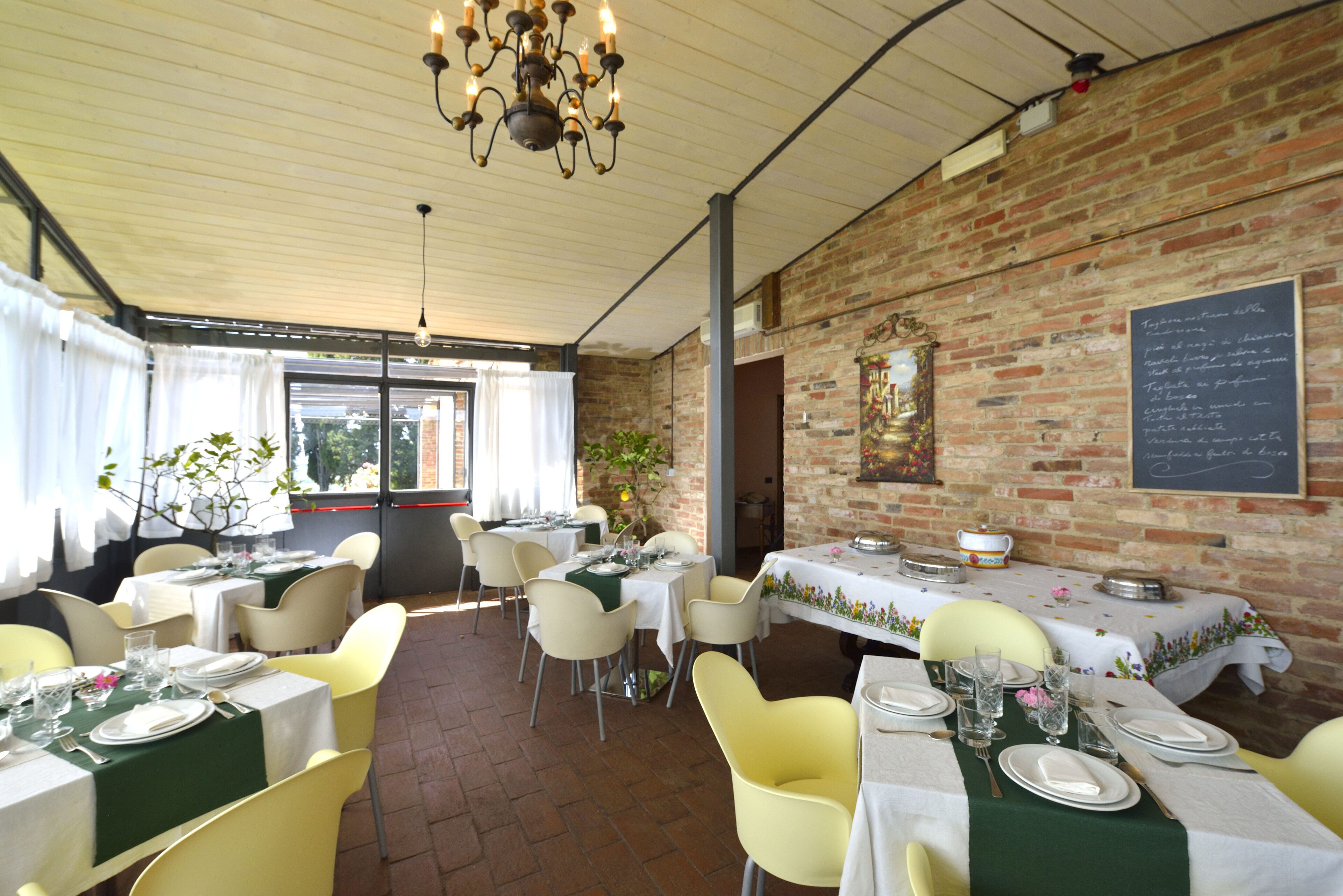A restaurant with brick walls, yellow chairs, and tables set for dining.