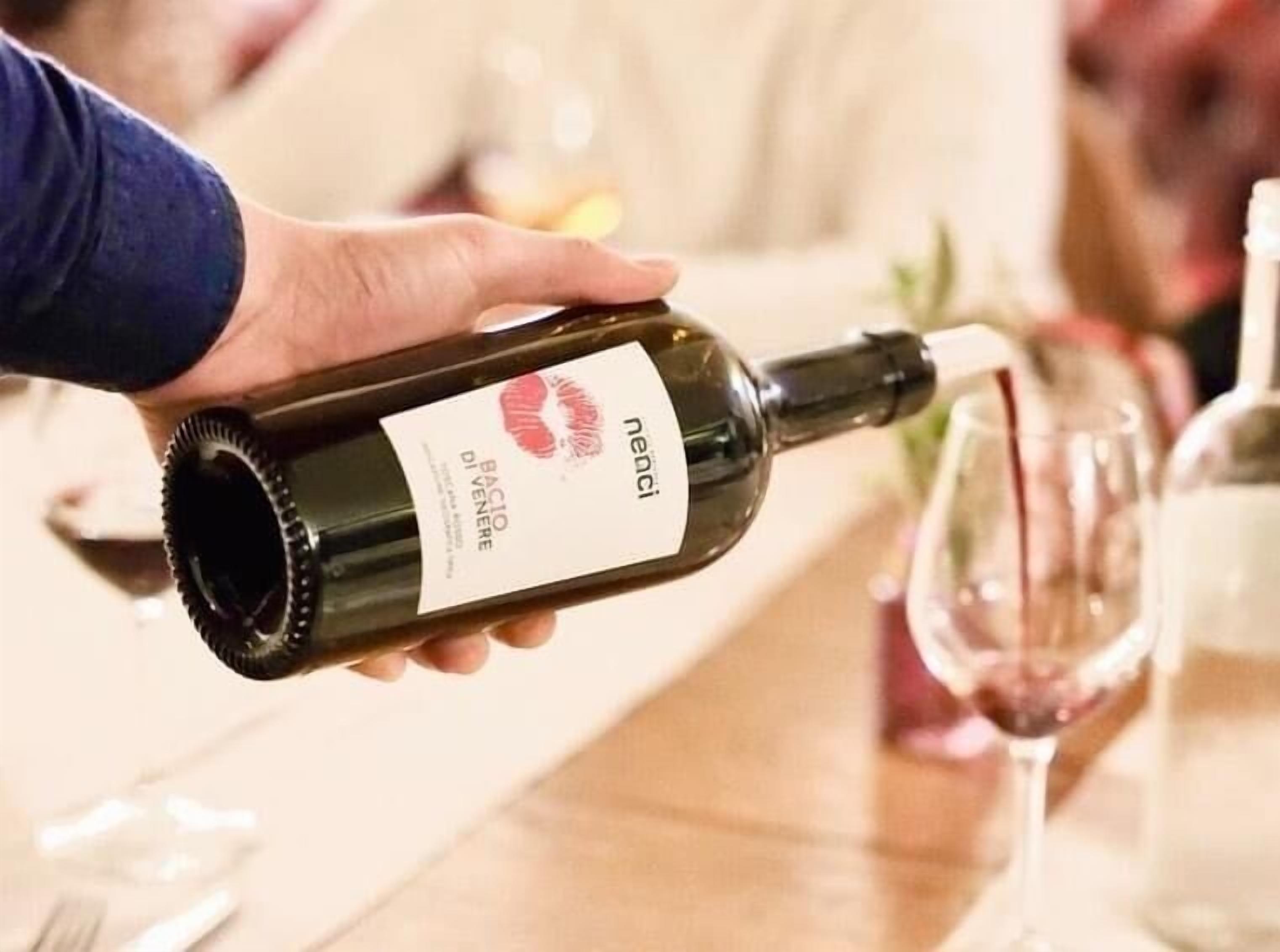 A person pouring wine from a bottle into a glass.