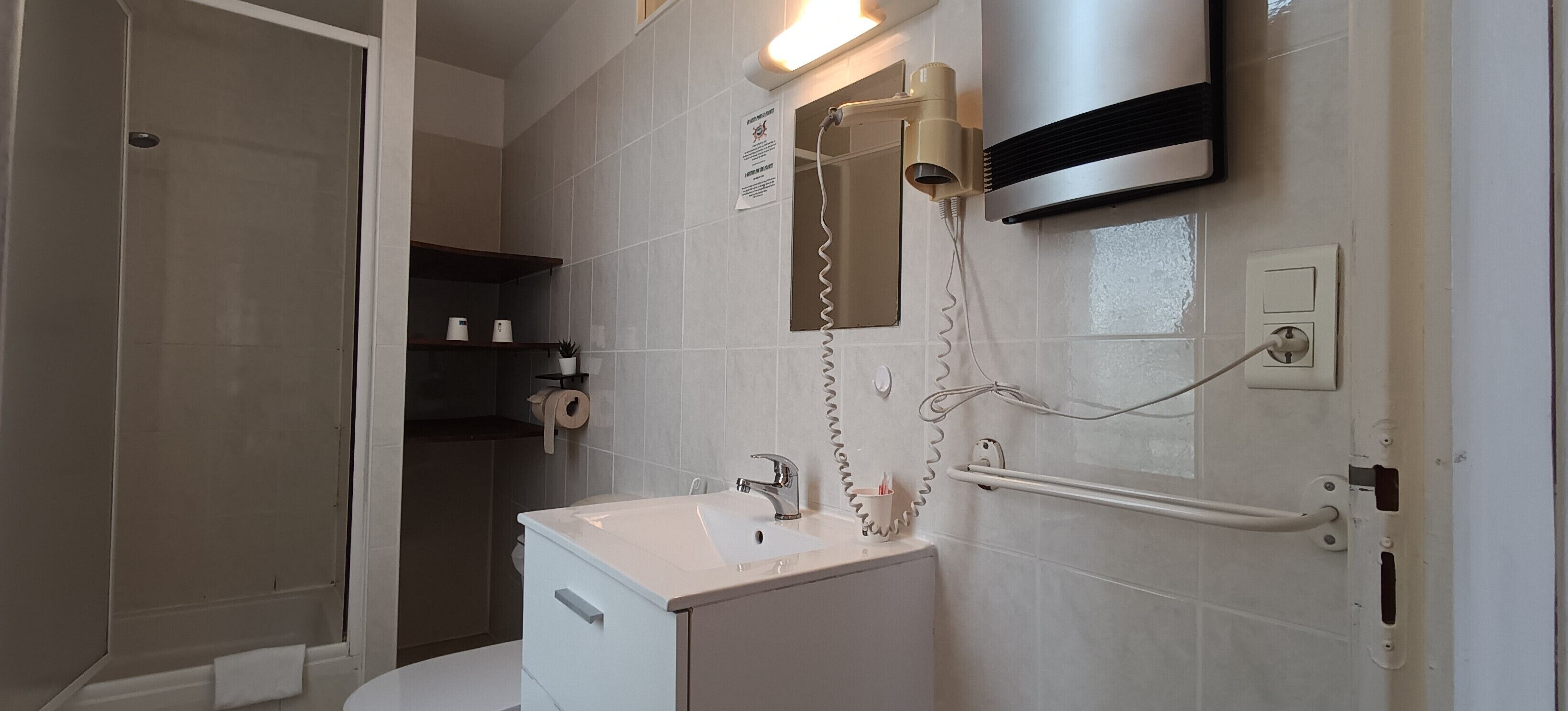A bathroom with a white sink, a mirror, a towel rack, and a shower area.