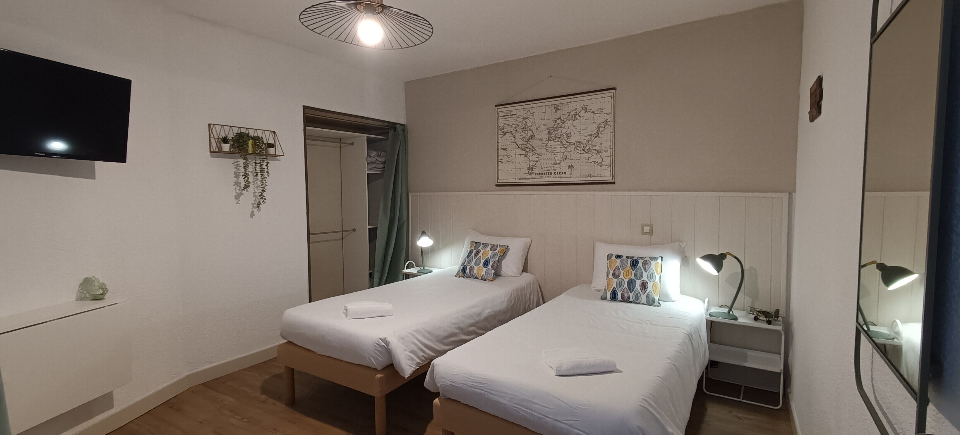 Un dormitorio con dos camas individuales, televisión, un mapa en la pared y un espejo.