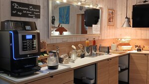 Una cocina moderna con cafetera, un espejo grande, armarios de madera y diversos utensilios de cocina.