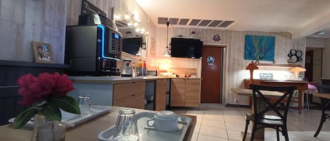 Cozinha moderna com micro-ondas integrado, máquina de café e televisão de tela plana.