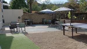 Un espacio al aire libre con mesas, sillas, una mesa de ping pong y sombrillas.
