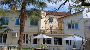 Un edificio de dos pisos con balcón, mobiliario exterior y palmeras.