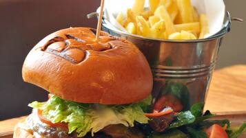 A burger with fries and salad on a wooden table.