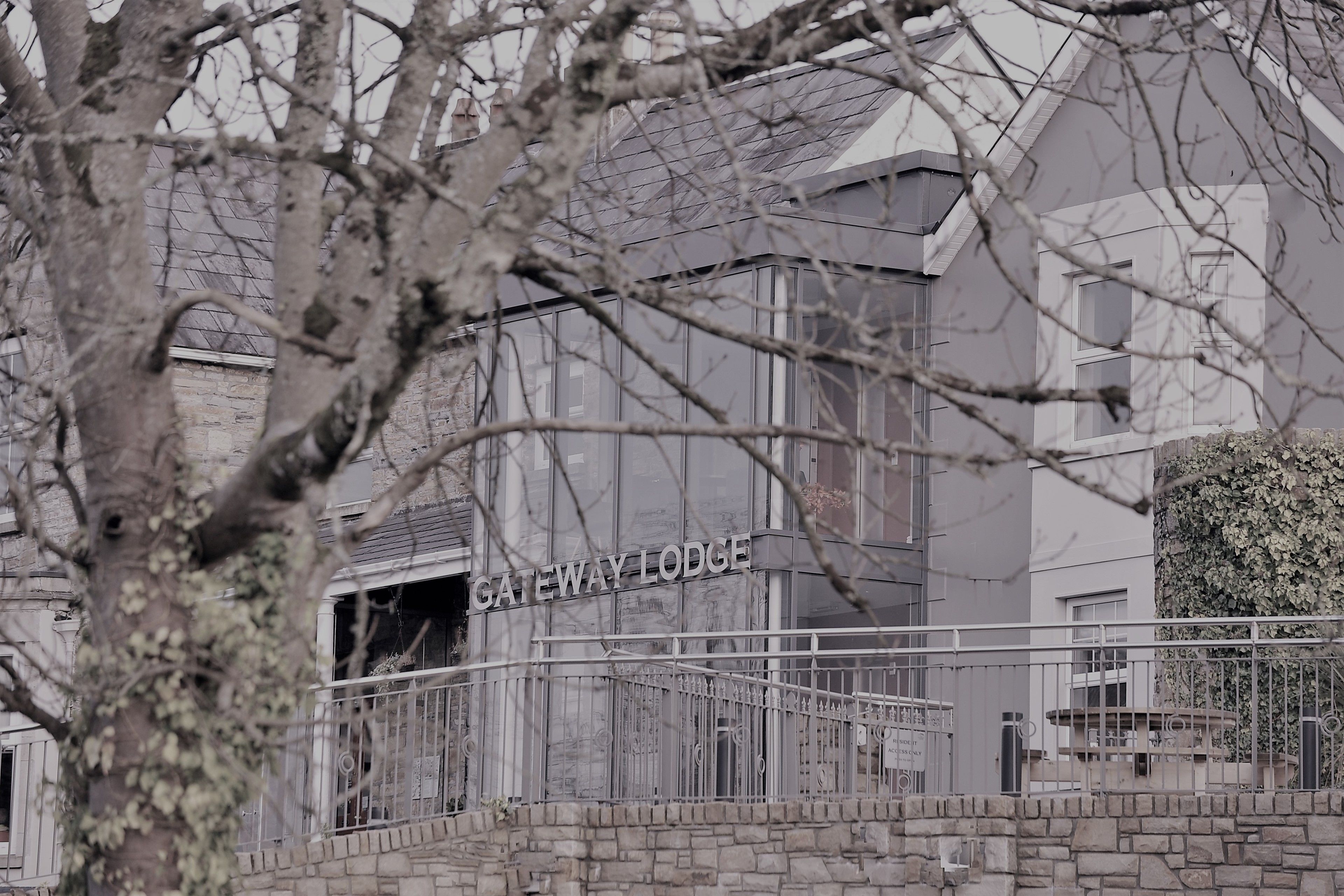 A building labeled "Gateway Lodge" with a stone wall and metal railing in front.