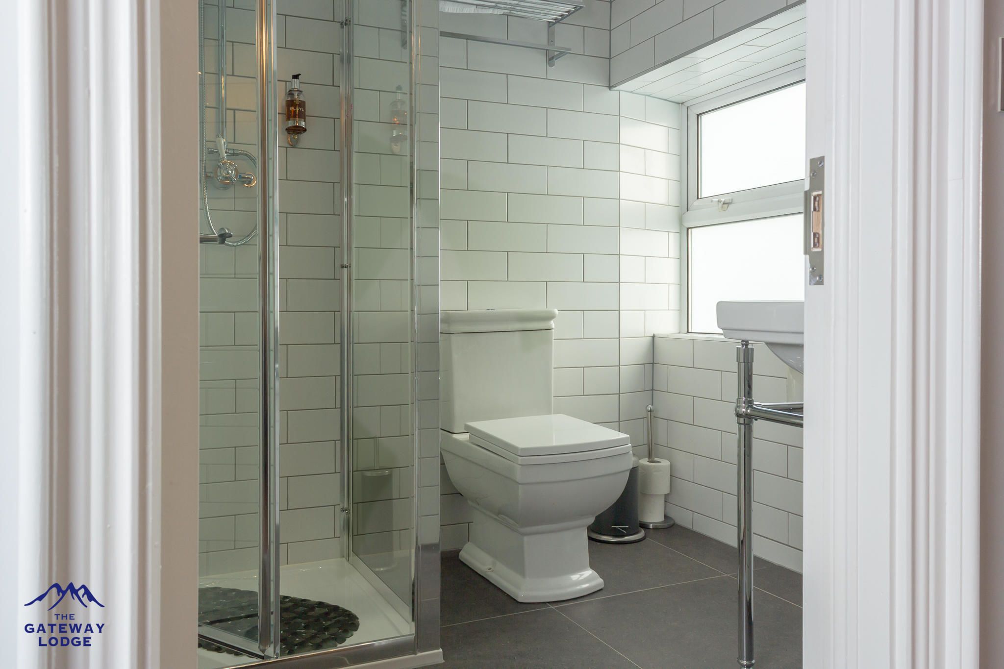 Un baño moderno con cabina de ducha de vidrio, inodoro blanco y lavamanos con grifo cromado.