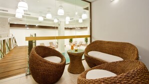 A modern interior with wicker furniture, a glass table, and a view of a pool area. - Earth and People Hotel & Spa (Sofia)
