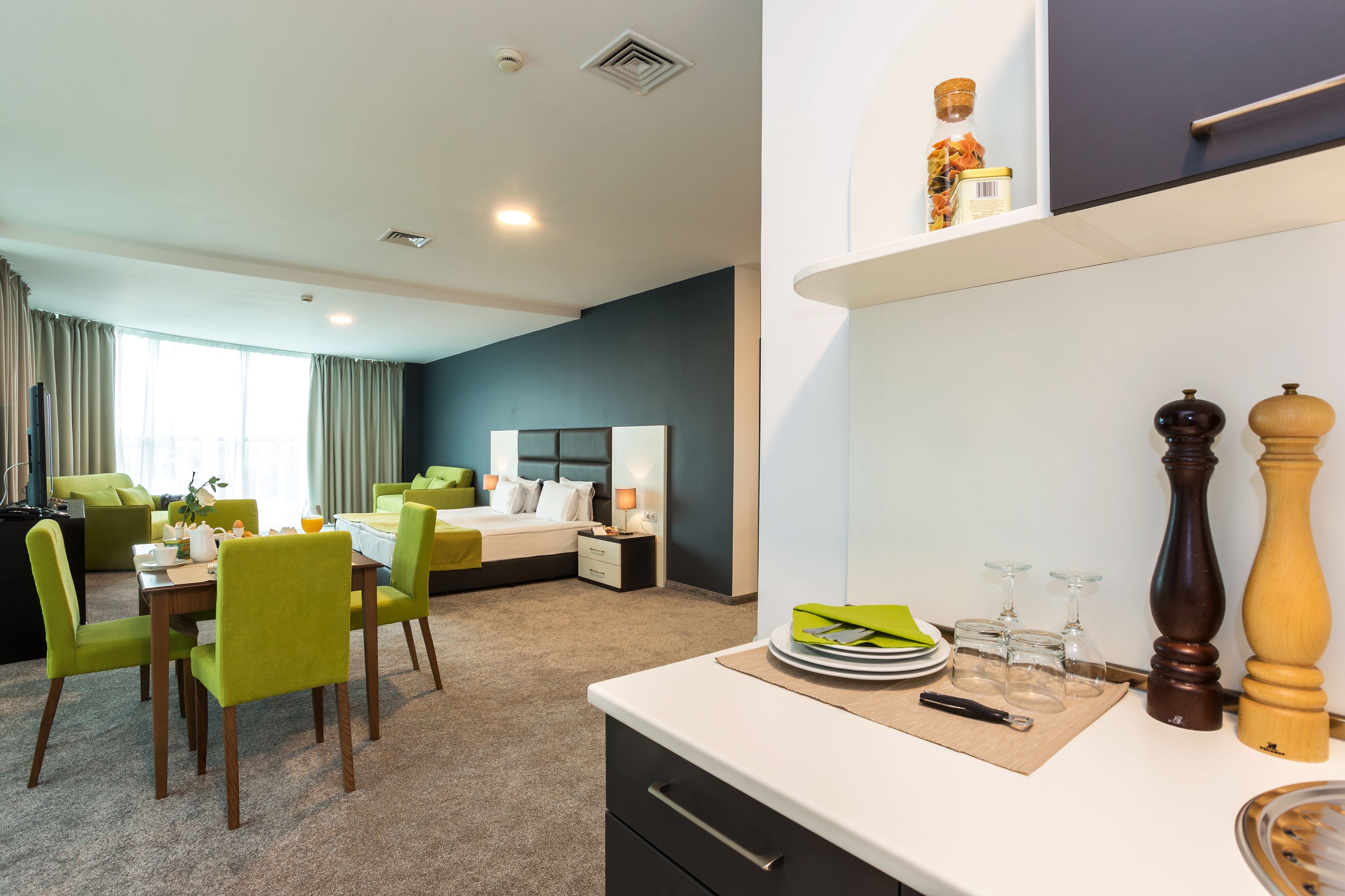 Ein modernes Hotelzimmer mit Essbereich, einem Bett mit Kopfteil und einer Küchenzeile.