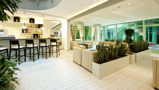 A modern hotel lobby with a bar area, seating, and indoor plants. - Earth and People Hotel & Spa (Sofia)