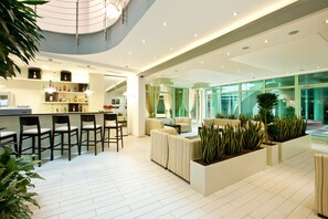 A modern hotel lobby with a bar area, seating, and indoor plants. - Earth and People Hotel & Spa (Sofia)