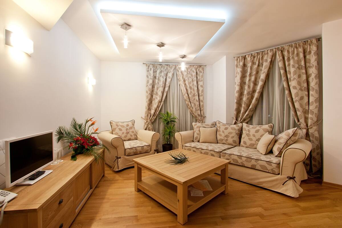 A modern living room with a sofa set, a coffee table, a TV, and a plant.