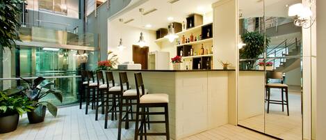 A modern bar area with a high ceiling, glass railings, and a seating arrangement with chairs.
