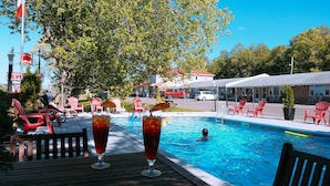 A poolside area with a wooden deck, red chairs, and a swimming pool. - Silverwood Inn & Suites (Fredericton)