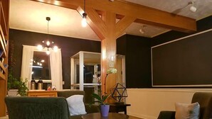 A cozy living room with a fireplace, a dining area, and a large window. - Silverwood Inn & Suites (Fredericton)