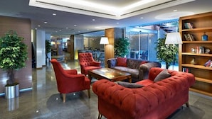 A modern lobby with red sofas, a coffee table, and a bookshelf. - Milport Hotel Levent (Istanbul)
