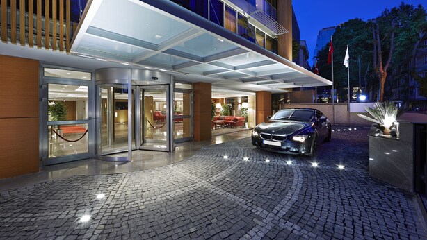 A hotel entrance with a glass door, a covered entrance area, and a cobblestone driveway. - Milport Hotel Levent (Istanbul)