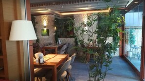 A dining area with a wooden table and chairs, surrounded by plants and a stone wall. - Milport Hotel Levent (Istanbul)