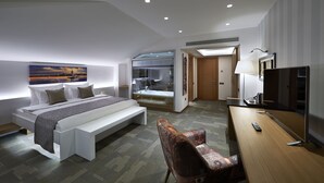 A modern hotel room with a large bed, a desk, a chair, a television, and a bathroom with a glass shower. - Milport Hotel Levent (Istanbul)