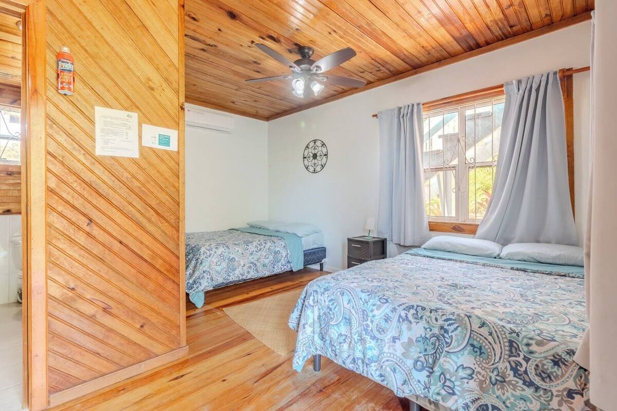 A bedroom with two beds, wooden ceiling, and a window with curtains.