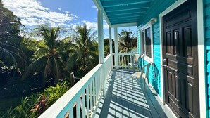 Un bâtiment turquoise doté d’un porche donnant sur un jardin tropical.