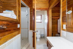 Un baño de cabaña de madera con ducha, inodoro y lavamanos.