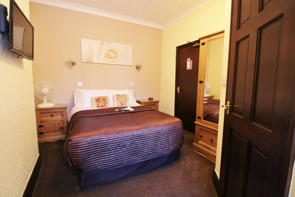 Une chambre à coucher avec un lit, des tables de chevet, un miroir et une porte.