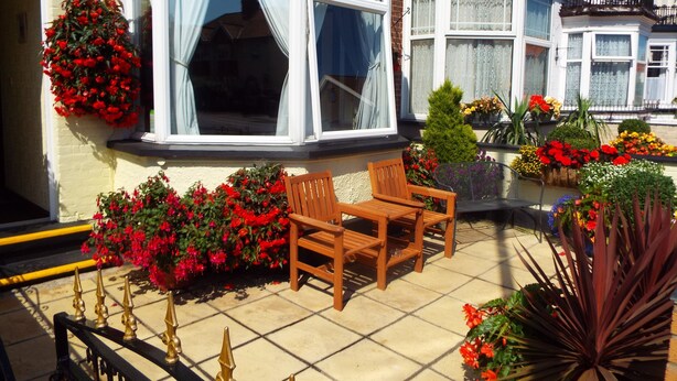 A corner building with a bay window, a wooden chair, and flower boxes. - Maluth Lodge (Great Yarmouth)