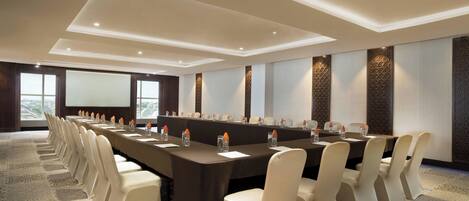 A conference room with a long table, chairs, and a projector screen.