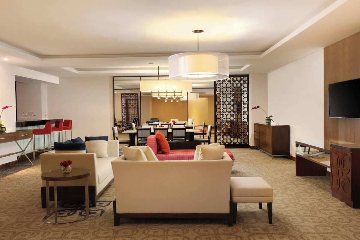 Une chambre d’hôtel moderne dotée d’un espace salon, d’un coin repas et d’une télévision.