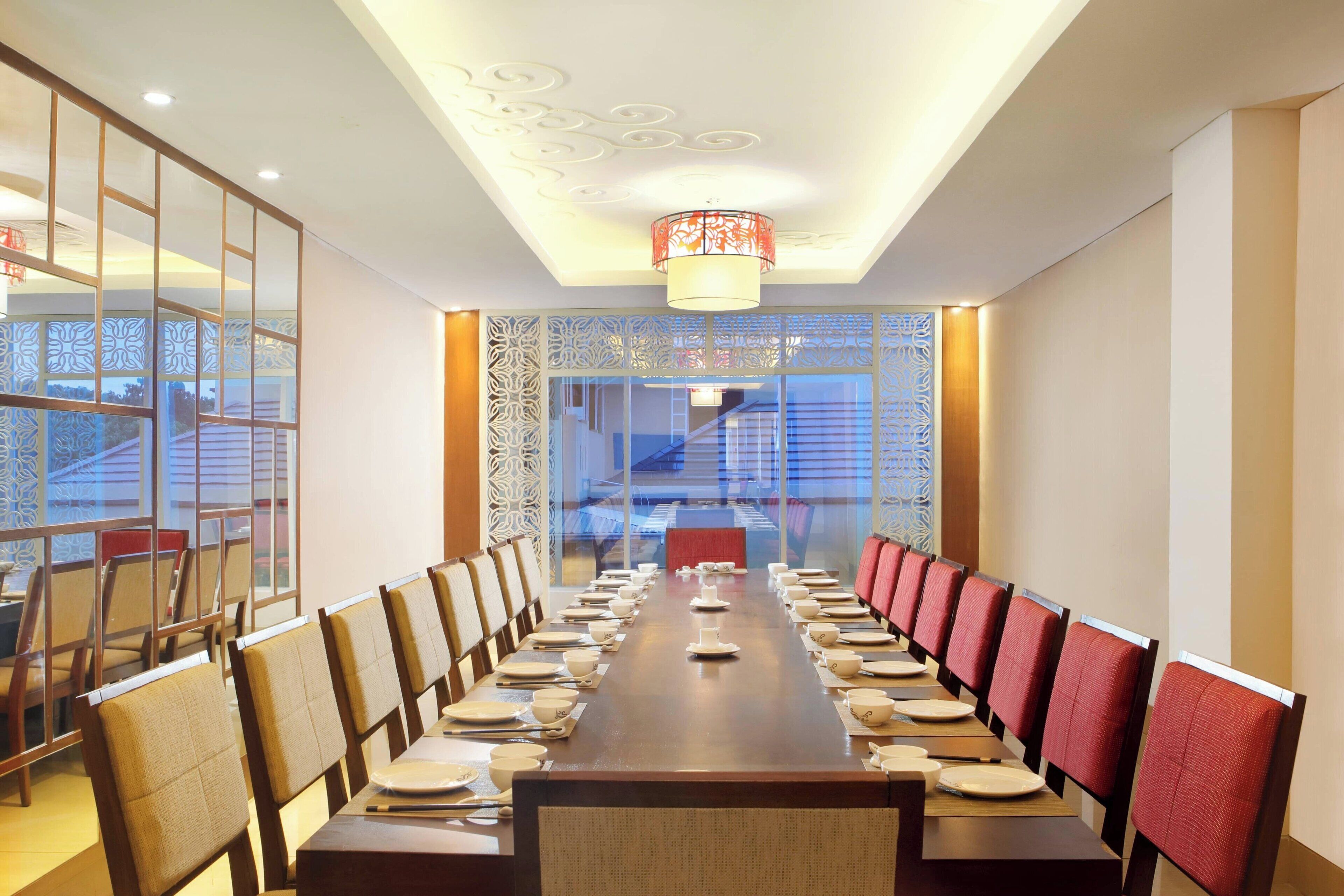 A conference room with a long table set for a meeting, surrounded by chairs, and a decorative ceiling.