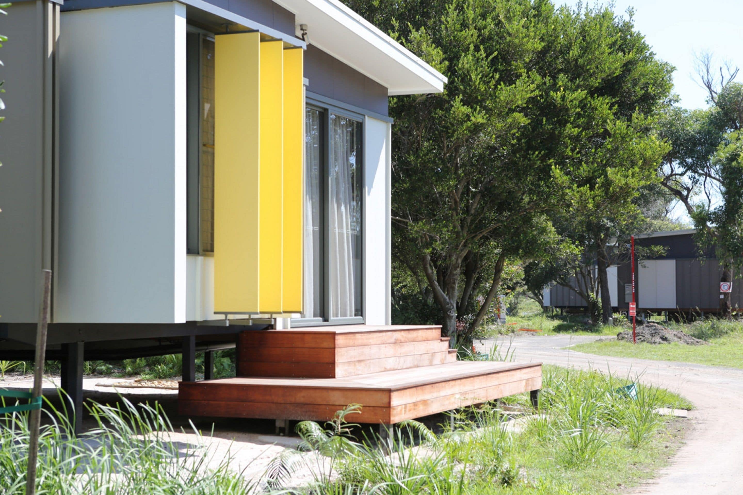 A modern house with a yellow door and a wooden deck.