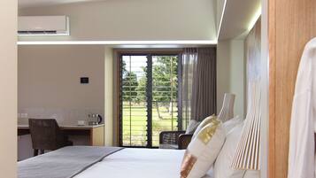 A modern hotel room with a large bed, a desk, and a view of the outdoors.