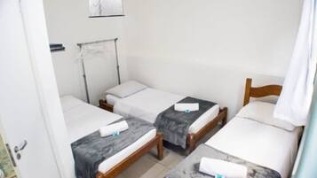 A room with two single beds, a wooden headboard, a small table, and a wall-mounted towel rack.