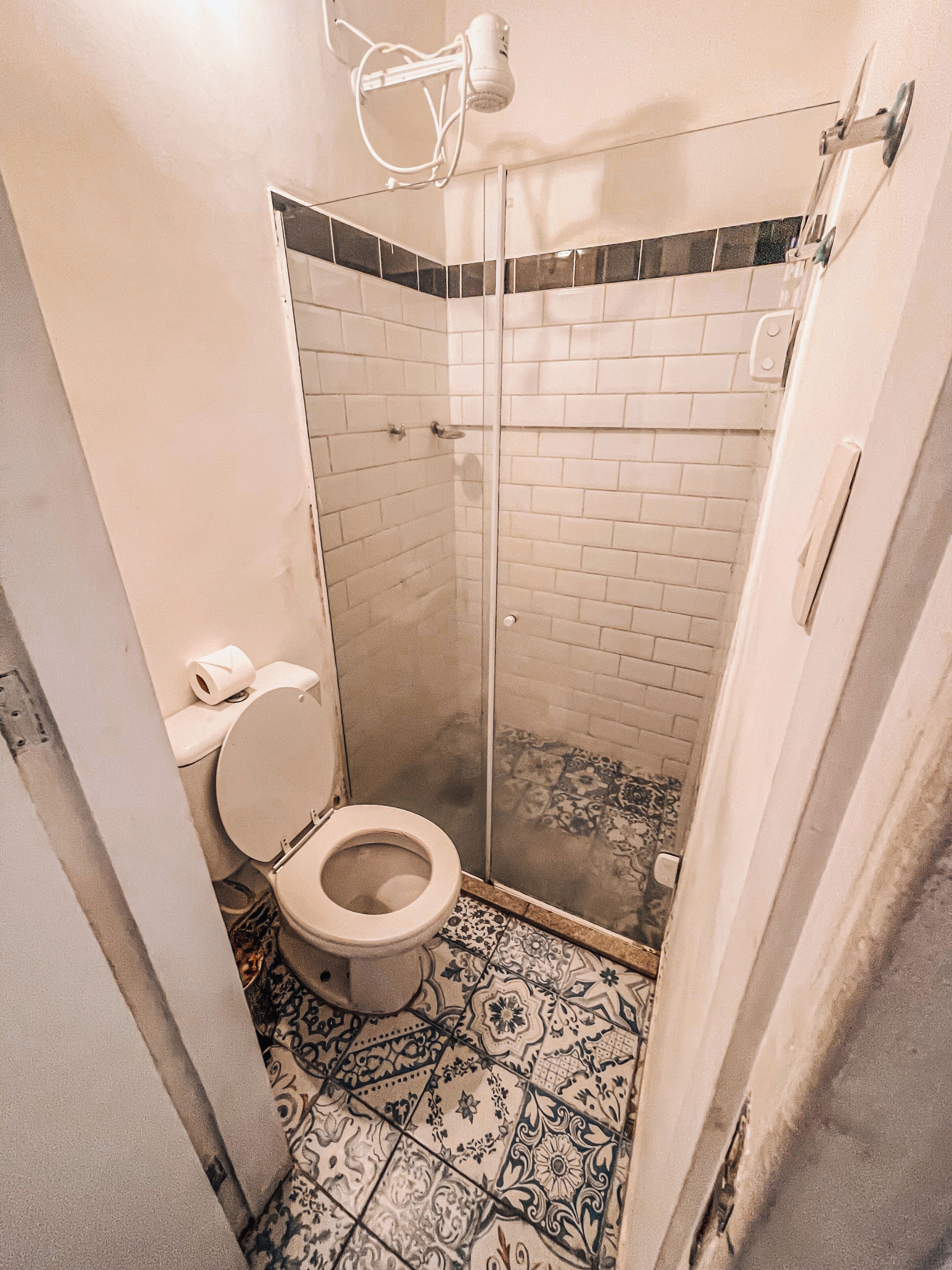 A bathroom with a toilet, a shower with a glass door, and patterned floor tiles.