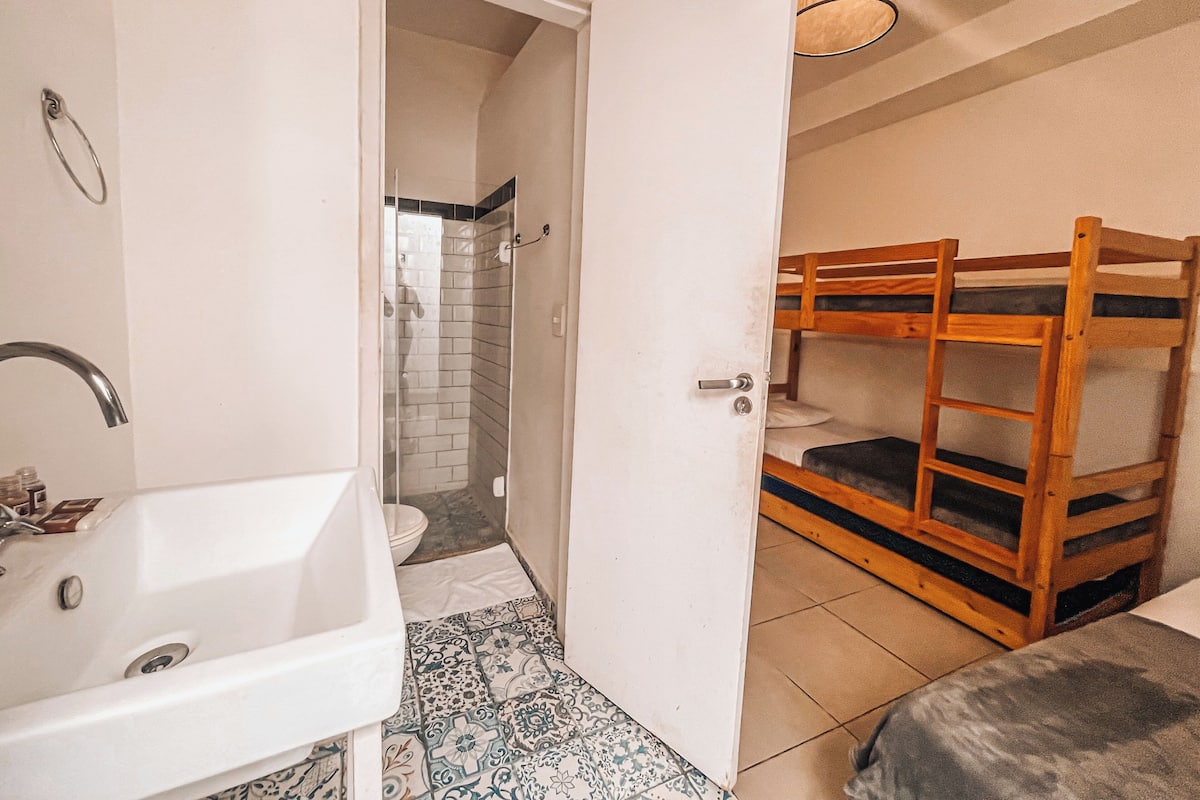 A bathroom with a white sink, a shower, and a wooden bunk bed.
