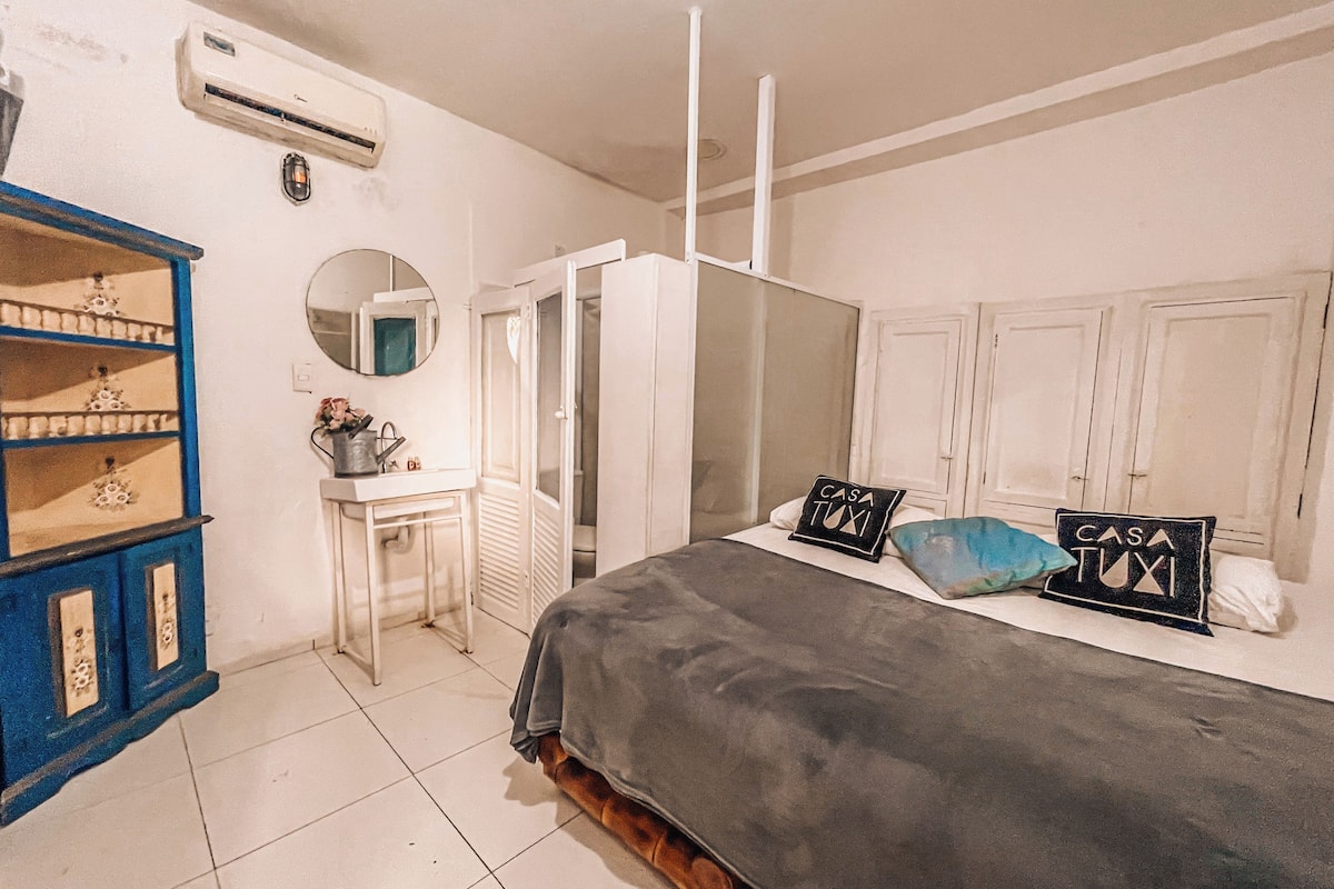 A bedroom with a bed, a wardrobe, a desk, and a shelf unit.