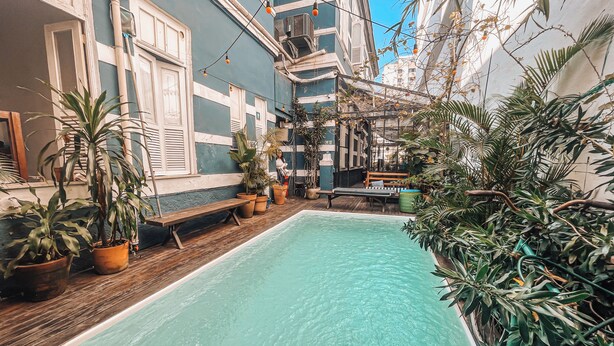 A courtyard with a swimming pool, potted plants, a wooden bench, and a bicycle. - Casa Tuxi (Rio de Janeiro)