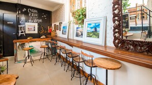 A bar area with wooden bar stools, framed pictures on the wall, and a mirror reflecting the interior. - Casa Tuxi (Rio de Janeiro)