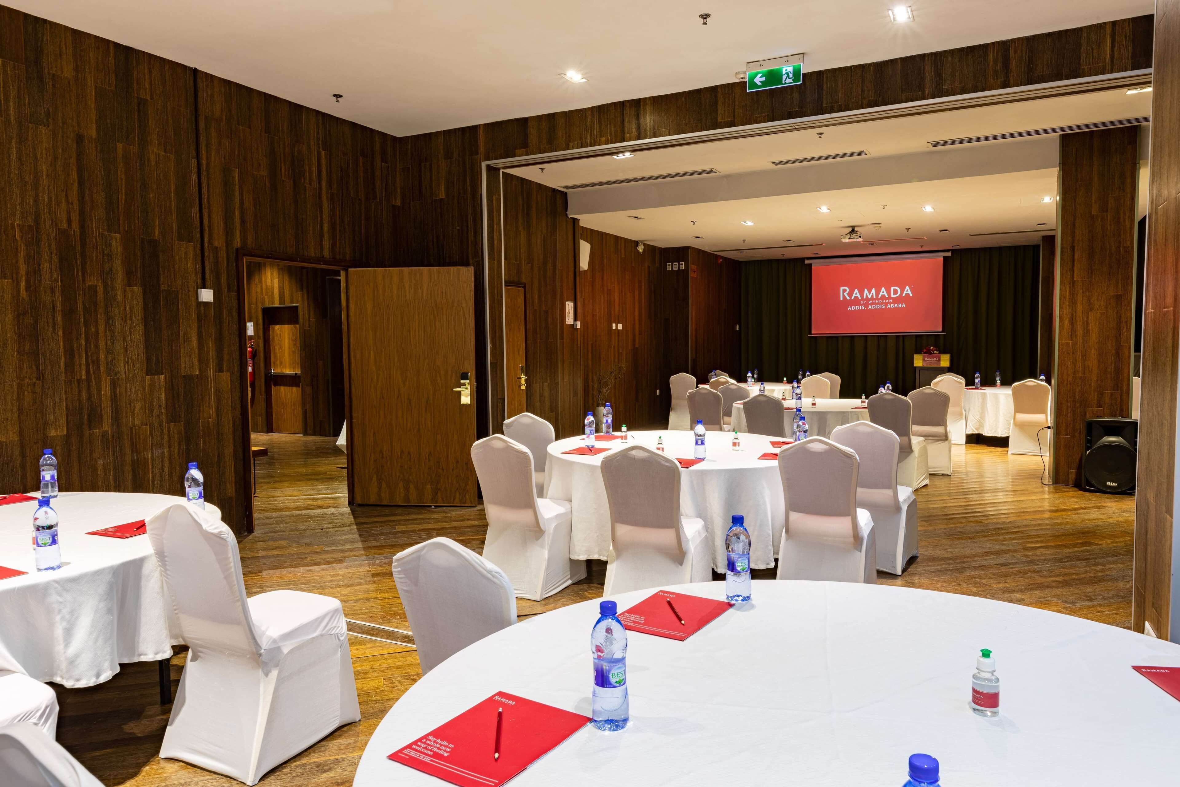 A conference room with round tables, white chairs, and water bottles.