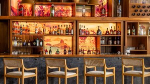 A bar area with wooden shelves displaying various liquor bottles, bar stools, and decorative artwork. - Ramada Addis, Addis Ababa (Addis Ababa)