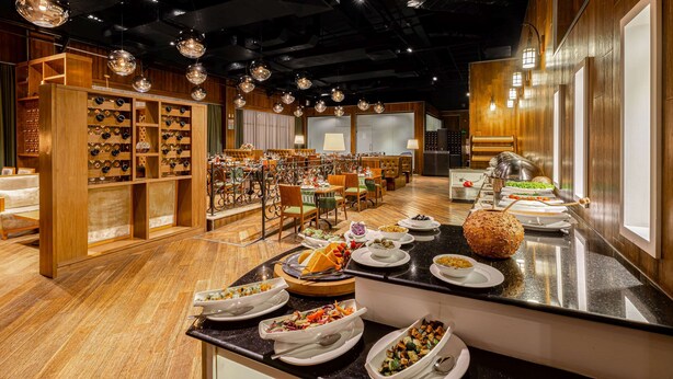A restaurant with multiple dining tables, a wine rack, and a buffet area. - Ramada Addis, Addis Ababa (Addis Ababa)