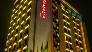A multi-story hotel with a prominent sign reading "RAMADA" and multiple flags displayed outside. - Ramada Addis, Addis Ababa (Addis Ababa)