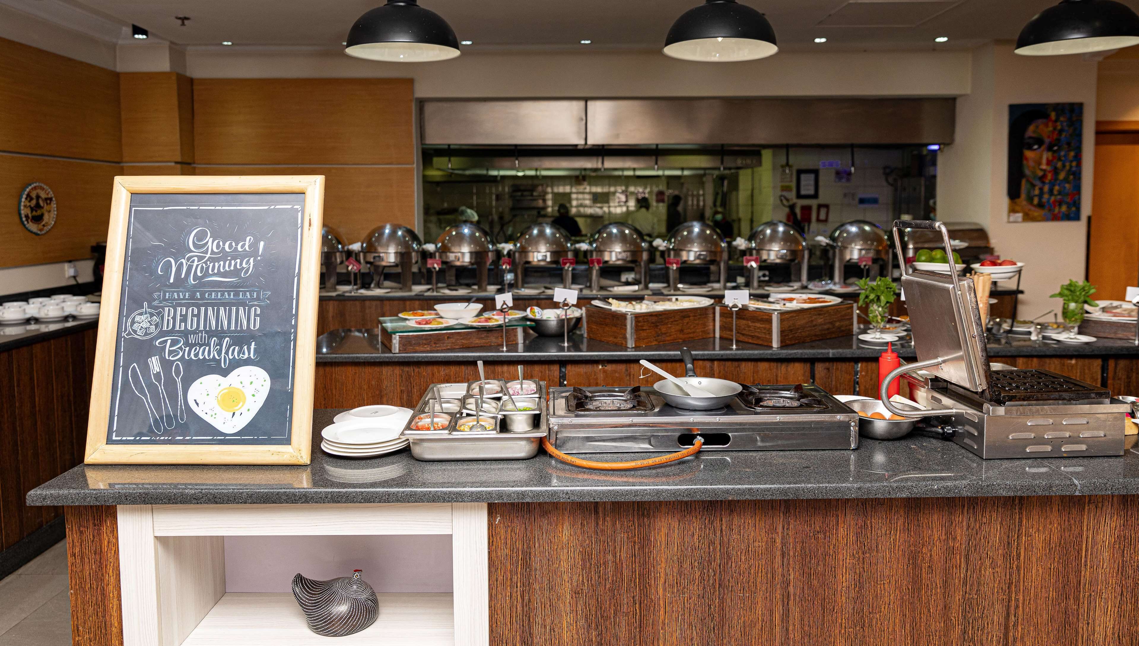 A breakfast buffet with various food stations and a chalkboard sign.