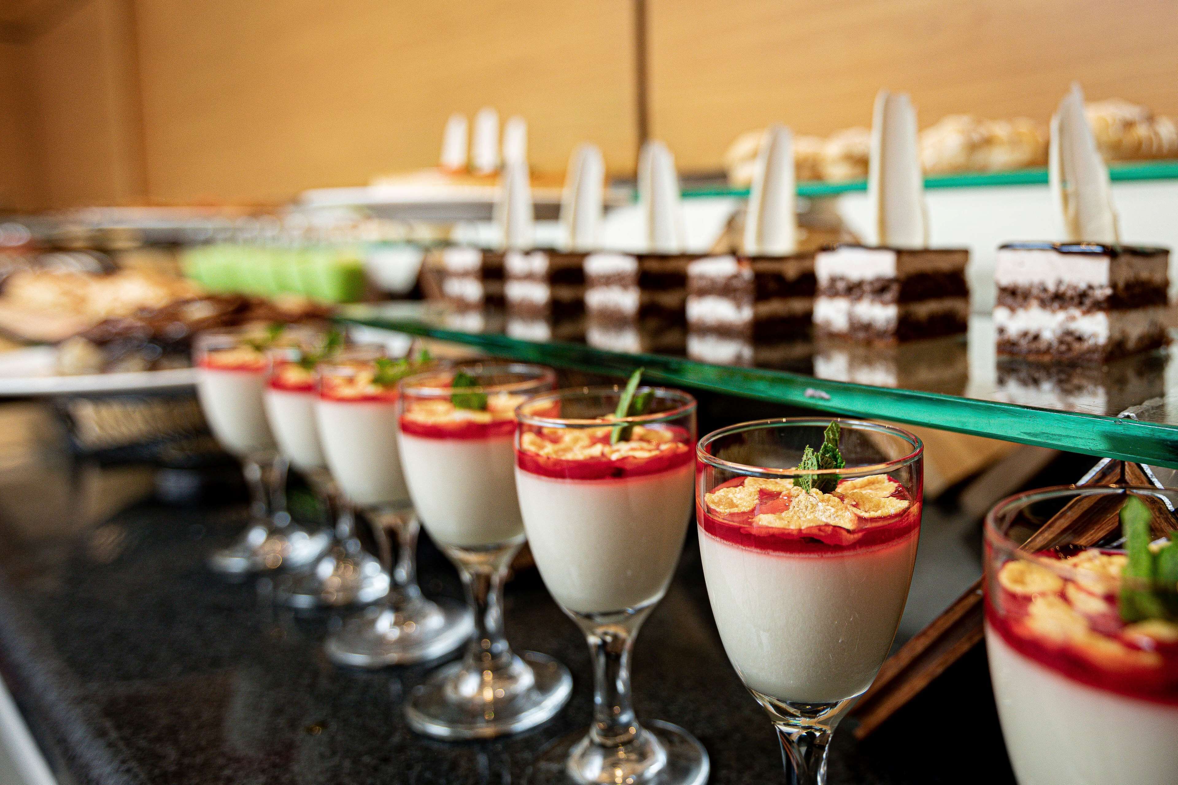 Ett dessertbord med olika sorters desserter i glas, bland annat lagerkakor och desserter med frukt som topping.
