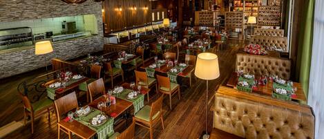 A restaurant with multiple dining tables, chairs, and a bar area.