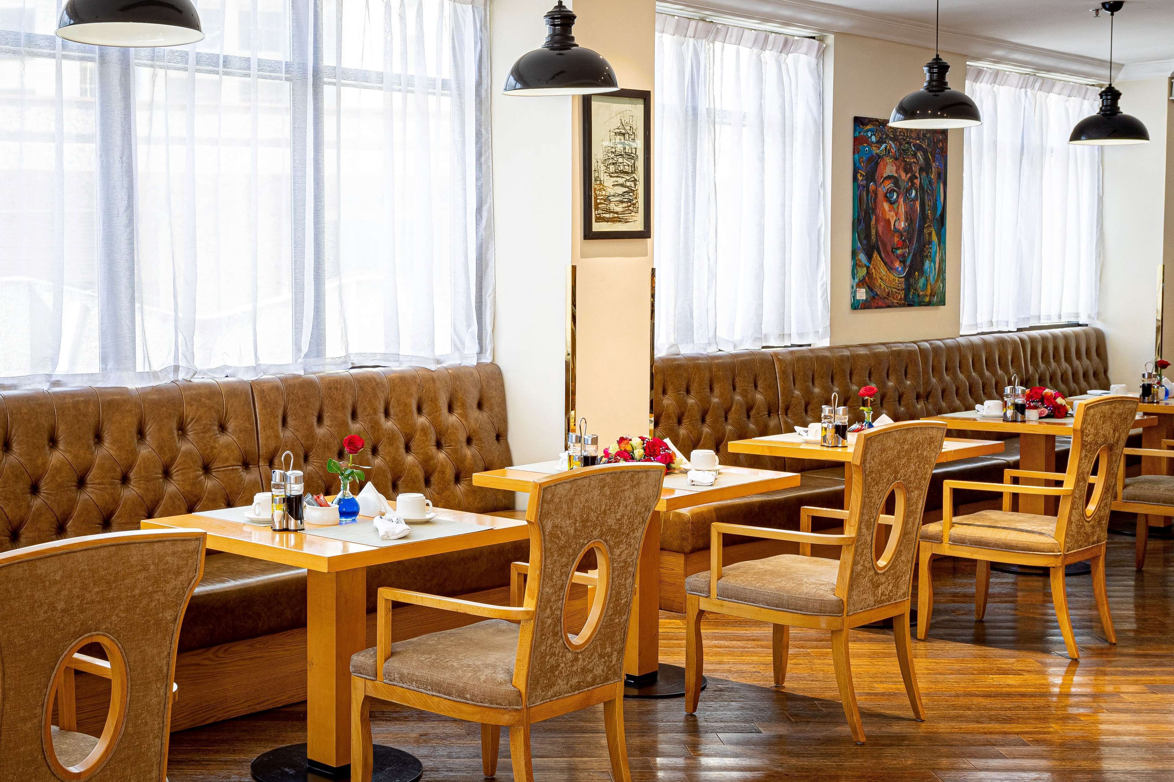 A restaurant with wooden tables and chairs, a cushioned bench, and artwork on the walls.