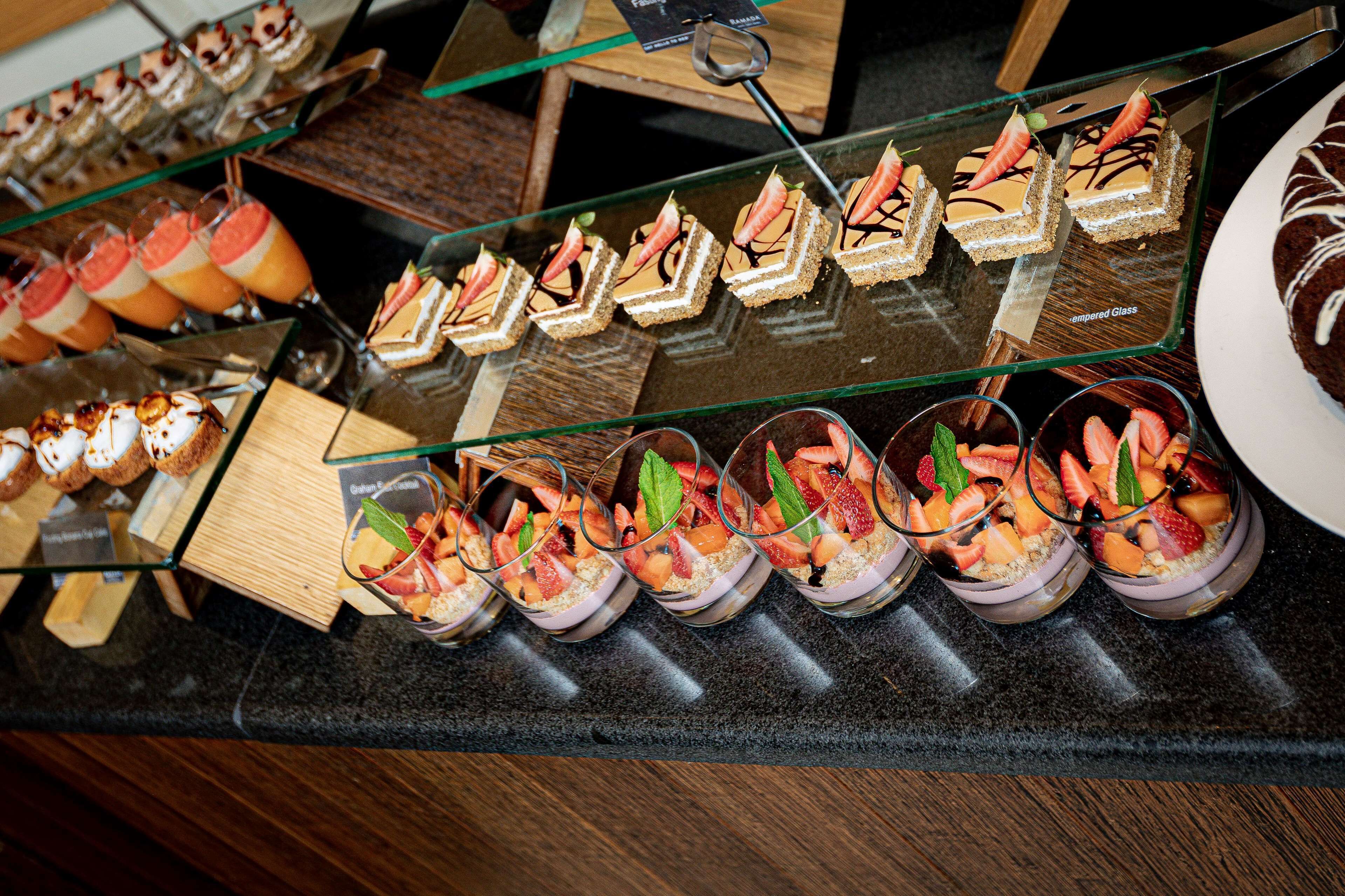 A variety of desserts displayed on a counter, including cakes and fruit-based desserts in glass cups.