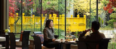 A cafe with a view of a yellow building and trees.